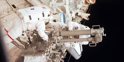 astronauts work on space shuttle robot arm